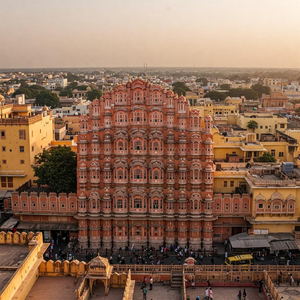 A panoramic view of Jaipur, Rajasthan's capital, showcasing its vibrant hues and intricate historical architecture. The iconic Hawa Mahal stands tall amidst bustling streets and ornate buildings, reflecting the rich culture and heritage of Rajasthan.