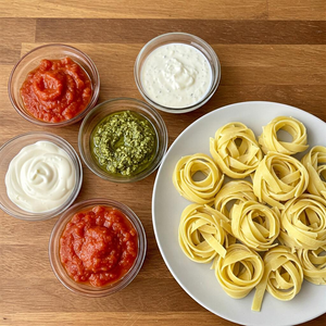 A variety of quick and easy pasta sauces in small bowls, served with fresh pasta on a wooden table